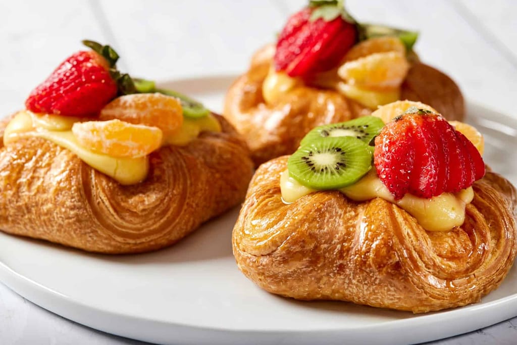 Fruit danish pastries topped with fresh strawberries and kiwi